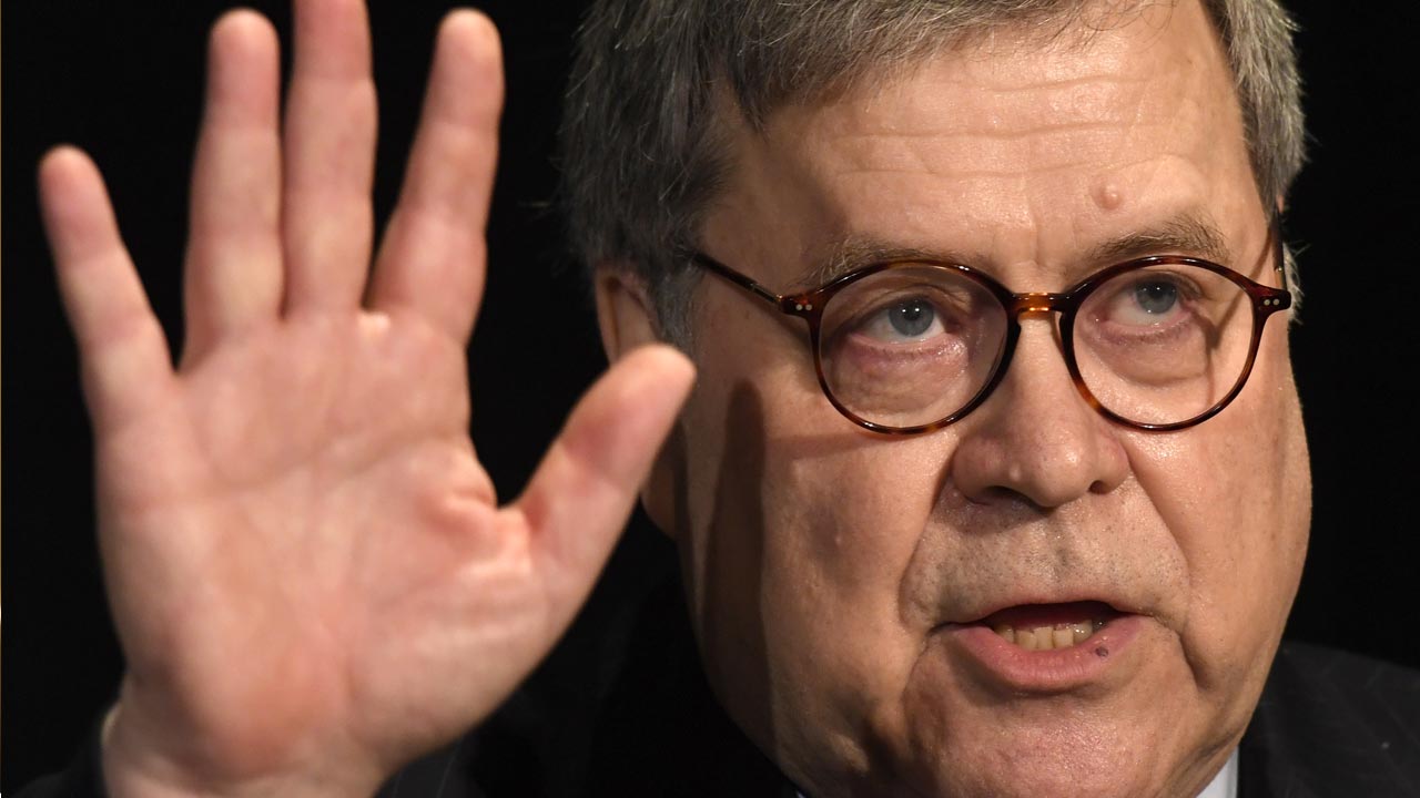 Photo of Attorney General William Barr putting his hand up